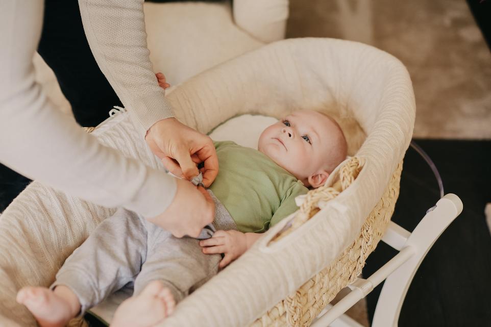 baby in green onesie lying on white crib